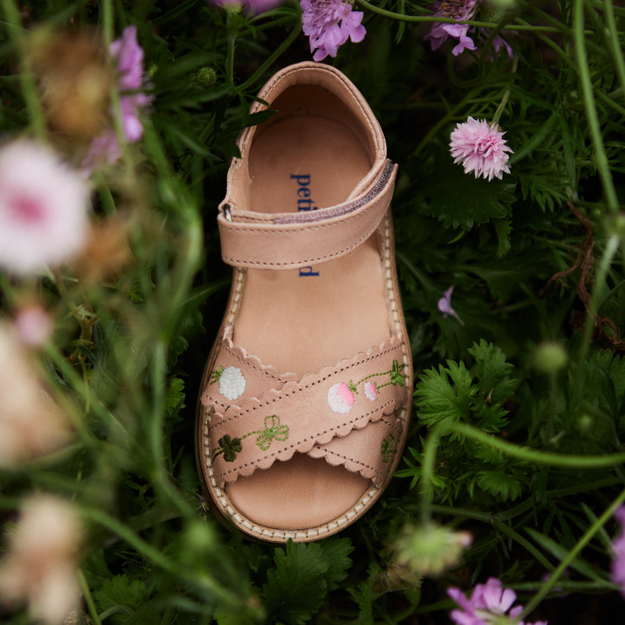 Photo des sandales brodées blooming rose de la collection Uniqua de chez Petit Nord prise dans l'herbe