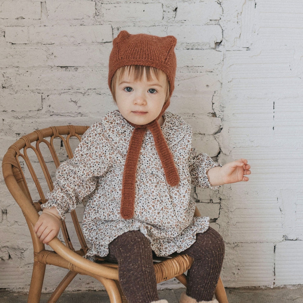 Bébé fille assise qui porte la robe bébé à imprimé automnal de chez Bùho