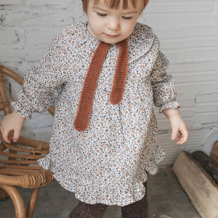 Bébé fille debout qui porte la robe bébé à imprimé automnal de chez Bùho