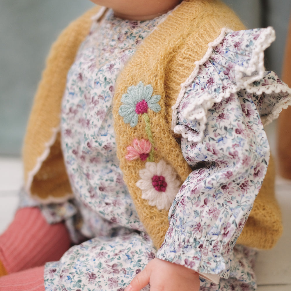 La combinaison Ounisa à fleurs Cream Retro Pansy de Louise Misha porté par un bébé assis