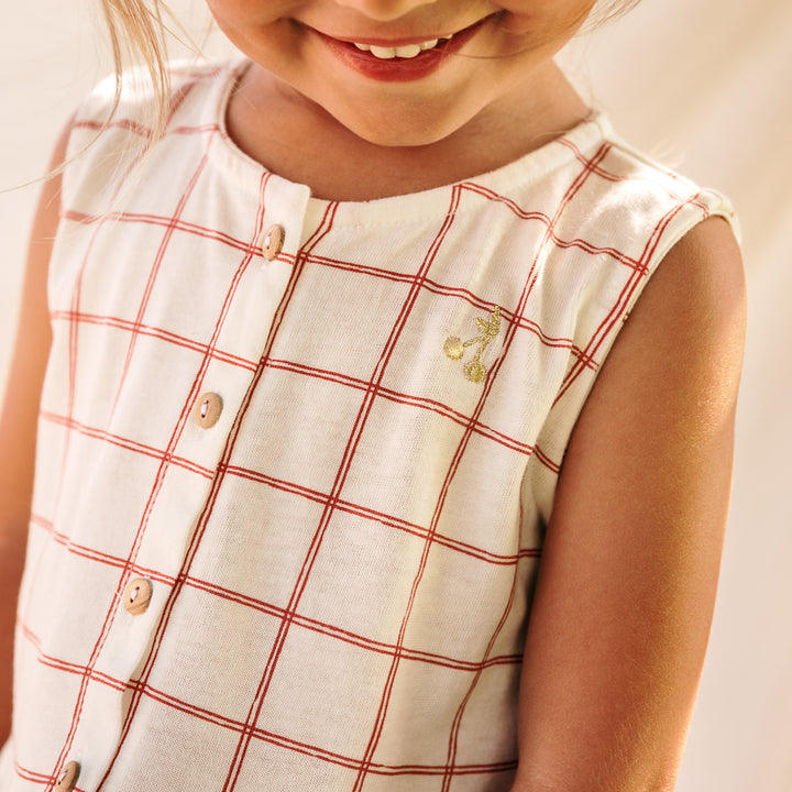 Photo des détails de la robe à cerises et à carreaux Romane de chez Les Petites Choses portée par une petite fille