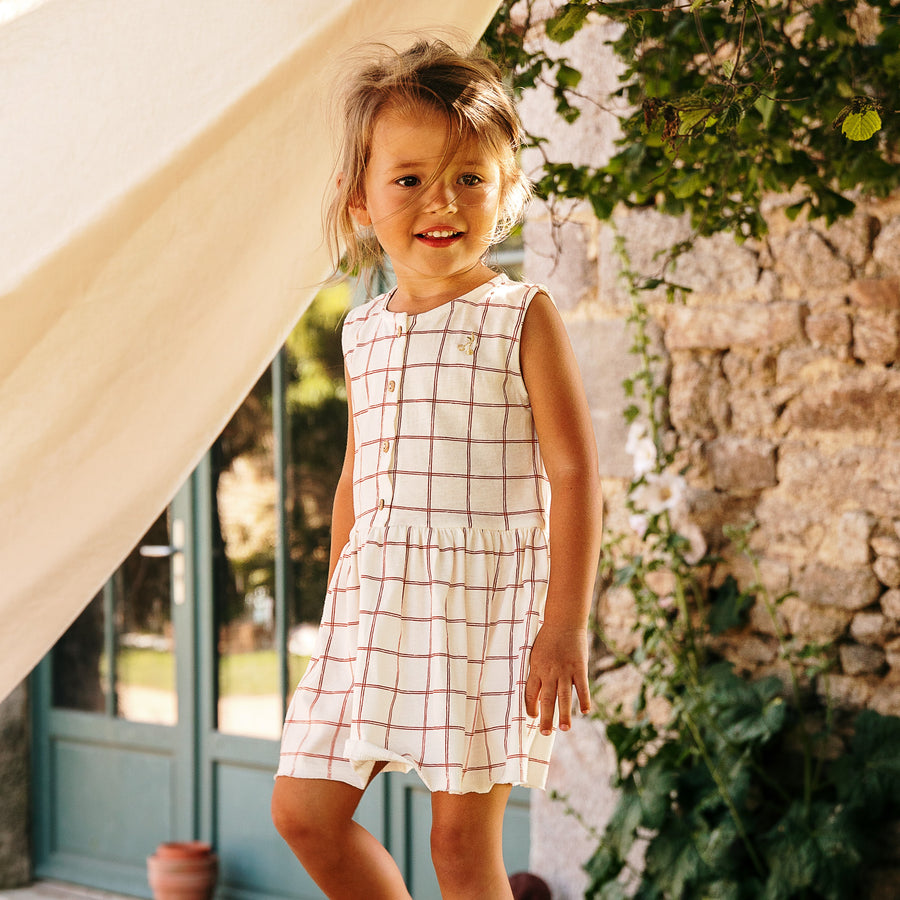 Photo de la robe à cerises et à carreaux Romane de chez Les Petites Choses portée par une petite fille 