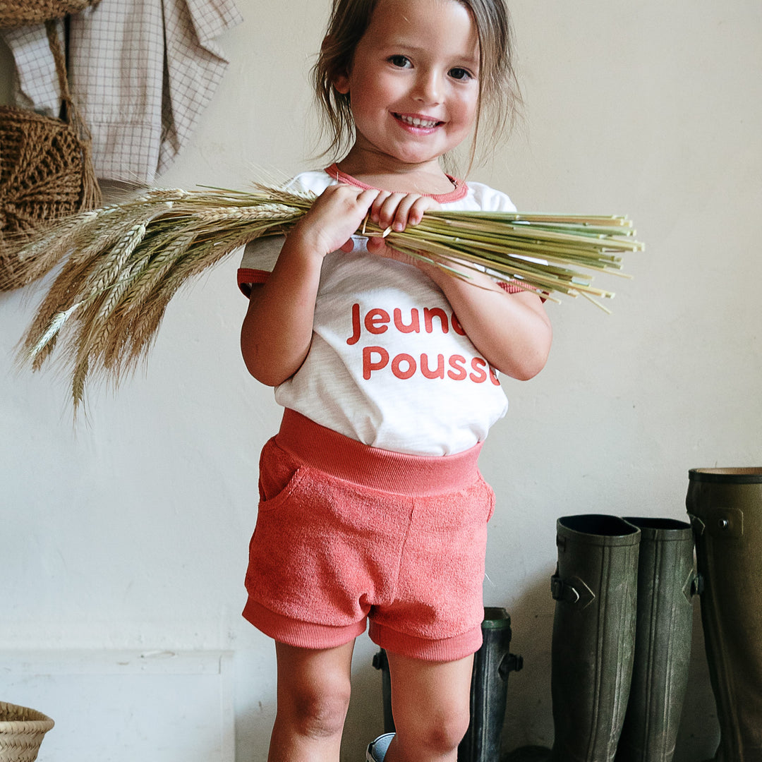 Photo du short paprika Kael de chez Les Petites Choses porté par une petite fille qui tient du blé dans ses mains