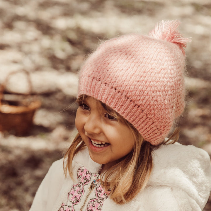 Fille qui sourit et qui porte la veste réversible Felvet de Louise Misha et le bonnet Alaska sienna de Louise Misha