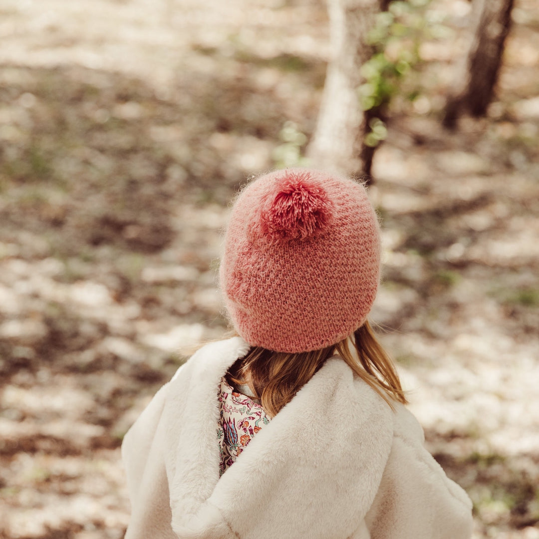 Fille de dos qui porte la veste réversible Felvet de Louise Misha et le bonnet Alaska sienna de Louise Misha